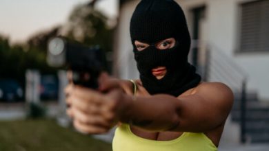 A masked woman holding a gun