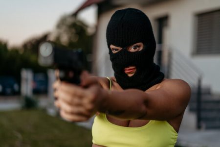A masked woman holding a gun
